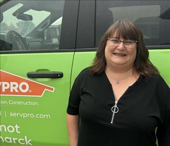 Lady with brown hair and glasses in front of green truck